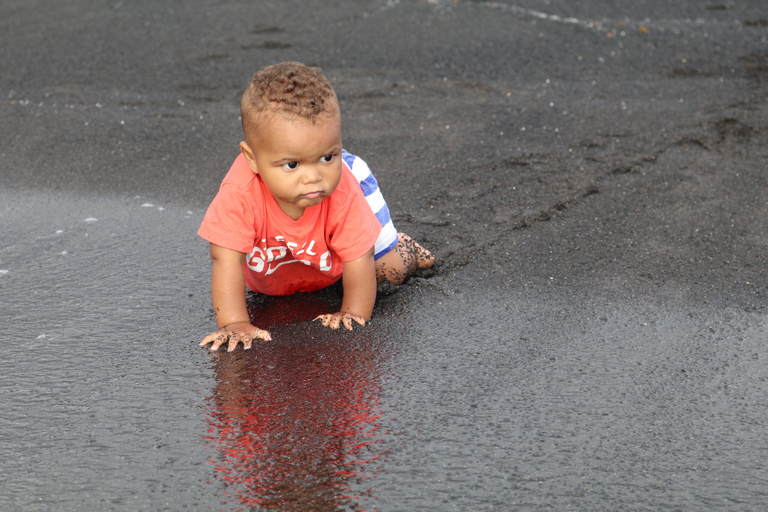 baby crawling in the black sand beach
